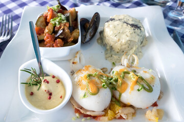 Delicious seafood restaurant dish from French cuisine - stewed calamari served with tomato and orange salsa, vegetable ratatouille, rice and catch of the day - mussels 