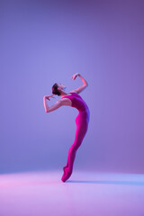 Strong. Young and graceful ballet dancer isolated on purple studio background in neon light. Art, motion, action, flexibility, inspiration concept. Flexible caucasian ballet dancer, weightless jumps.