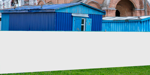 long blank white hoarding with mockup on construction site with blue builders house