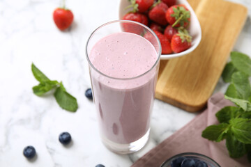 Tasty milk shake and berries on light table, closeup
