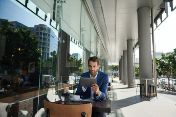 Businessman using a digital tablet at a sidewalk cafe table