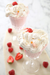 Tasty milk shake with whipped cream and fresh berries on light table, closeup