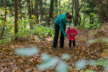 Mother and daughter exploring autumn forest together.