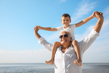 Cute little boy with grandfather spending time together near sea