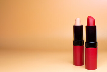 Two lipsticks in trendy colors, isolated on orange background