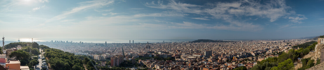 Fototapeta na wymiar Wide panorama of Barcelona, Spain, viewed from the Bunkers of Carmel on a sunny day with blue skies. Picturesque panorama of morning Barcelona.