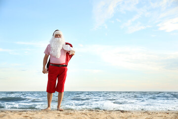 Santa Claus having fun on beach, space for text. Christmas vacation