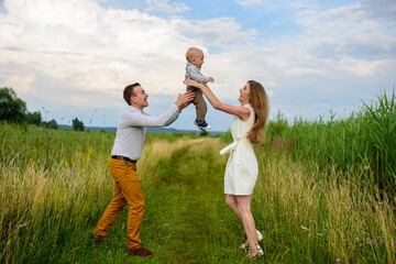 Fototapeta premium Parents throw their one-year-old son into the sky.