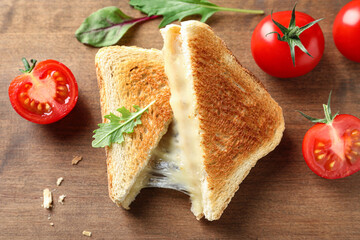Tasty toast sandwiches with cheese and tomatoes on wooden board