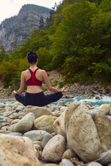 Yoga classes in nature. The concept of playing sports alone. Social exclusion. A woman does yoga on rocks, near a mountain river flows