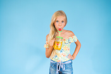 Beautiful blonde girl drinking a juice on blue background