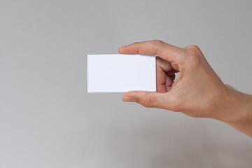 Hand holding empty white business card.