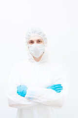 A man in a protective suit and face mask looks at the camera with his arms folded. Isolated on a white background.
