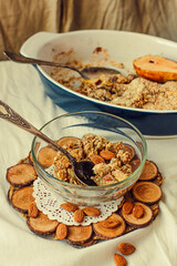 Pear crumble with cinnamon and a dessert spoon in a ceramic form on a light linen cloth, selective focus.Healthy autumn morning breakfast or dessert