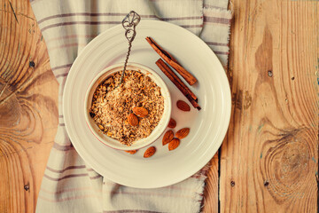 Fruits and nuts crumble pie in a portion form and a dessert spoon. Dessert with oatmeal, almonds and cinnamon  on wooden table, selective focus. Top view