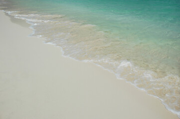 Pristine white sand beach and clear turquoise sea on a Caribbean island, summer vacation concept or working remotely from around the world, holidays envy, tropical marine background with copy space