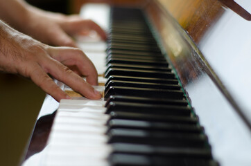 Fototapeta premium The fingers of a man play the piano. Male hands on the piano keys.
