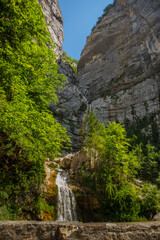 Fototapeta na wymiar Canyon des Ecouges in France on a sunny day. Two waterfalls, one in sun and one in the shade in a narrow and steep mountain gorge.