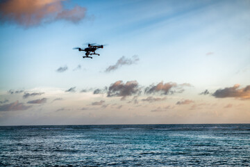 Fototapeta na wymiar Drone silhouette flying over a tropical island. Vacation, travel and discovery concept