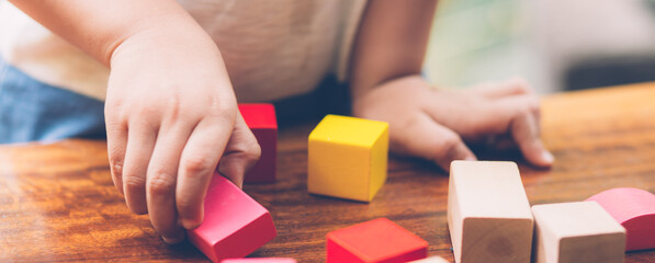 Closeup hand of boy playing wooden block toy on table for creative with enjoy, happy child learn...