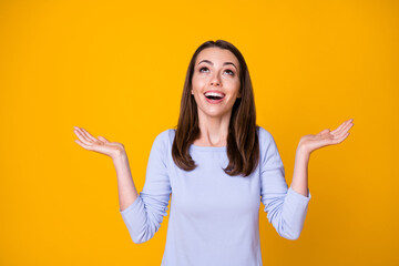 Photo of attractive pretty cheerful lady good mood open mouth excited overjoyed look up empty space sky catch arms rain drops wear casual shirt isolated vibrant yellow color background