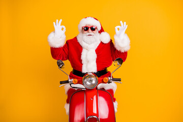 Portrait of his he nice confident cheery lucky Santa riding moped showing double ok-sign advert winter season discount isolated bright vivid shine vibrant yellow color background