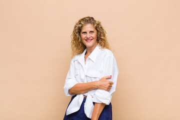 Middle age woman laughing shyly and cheerfully, with a friendly and positive but insecure attitude
