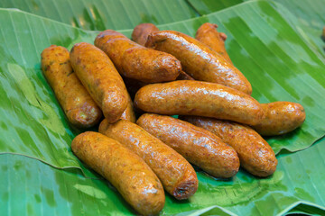 Fried northeastern spicy sausage on banana leaf. Famous local food made from pork and rice of Thailand. Thai sausage.