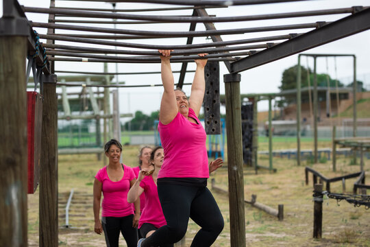 Woman hanging on monkey bars at a boot camp
