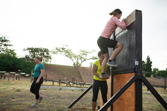 Woman climbing on a obstacle wall at boot camp