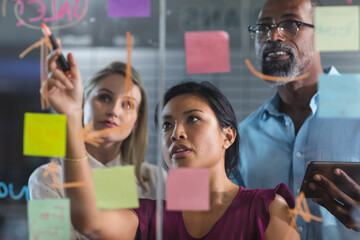 Young businesswoman writing on glass board at modern office