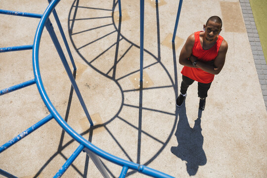 Top view of Black African American man with prosthetic leg standing with his arms crossed in the park