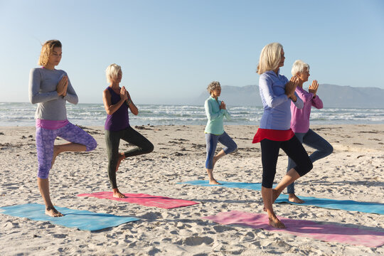 Women practicing yoga on beach