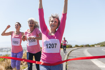Group of woman running towards the finish line ribbon