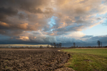 Fototapeta na wymiar Agricultural fields and clouds highlighted by the setting sun on the sky