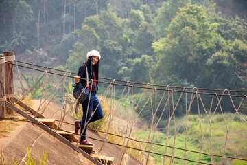 Fototapeta na wymiar Travelers thai women visit walking on wooden suspension bridge in Pang Ung lake in Pang Oung forest park or Switzerland of Thailand in authentic Chinese village Ban Rak Thai in Mae Hong Son, Thailand