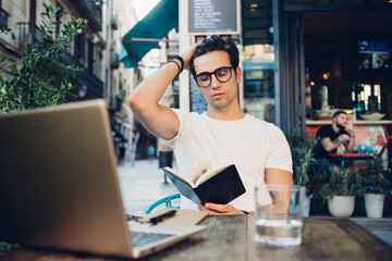 Clever man reading book on terrace of Spanish cafe