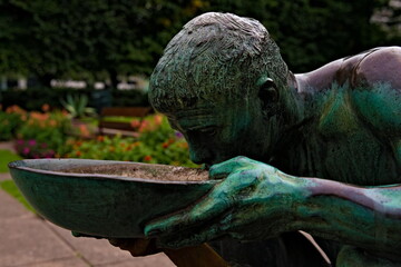 Statue of a thirsty poor man drinking from a plate.