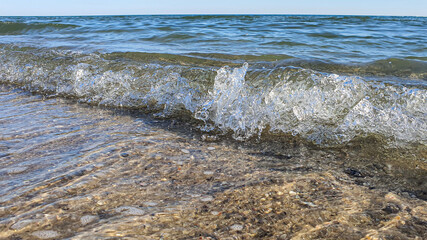 Fototapeta na wymiar Seascape. Azure color of water, waves foaming on the shore. Selective focus. Summer rest.