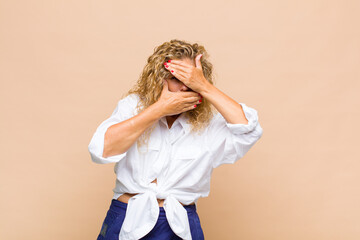 Middle age woman covering face with both hands saying no to the camera! refusing pictures or...