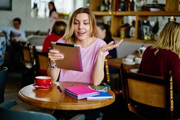 Excited woman checking news on tablet in cafe