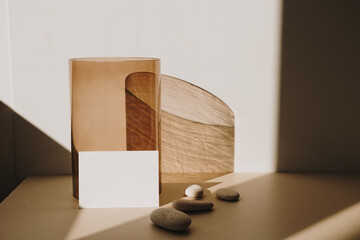 Blank paper sheet card with mockup copy space and tan glass vase with sunlight shadow on white...
