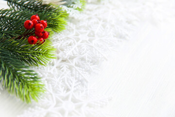 fur-tree branches, red berries, decoration on white wood, top view, copy space.