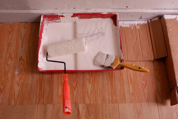 Paint roller and paint brush in the tray. The painter is doing the wall