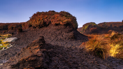 Island of old cut turf or peat, highlighted by setting sun in beautiful scenery of Wicklow mountains. Clear, purple and blue sky n background