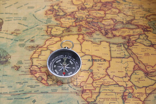 Classic round compass on background of old vintage map of world as symbol of tourism with compass, travel with compass and outdoor activities with compass