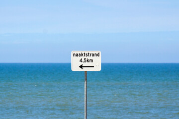 Sign on the beach indicating the distance to the nudist beach (in Dutch) 