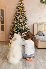 Christmas Child girl with dog Samoyed. New Year at home