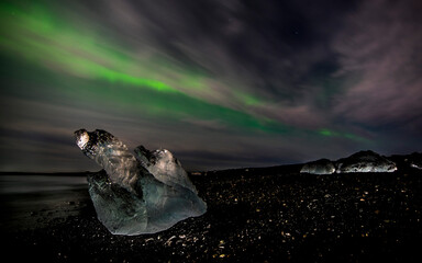 iceberg in iceland on the beach with aurora borealis