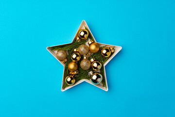 Star shaped plate with golden baubles on blue background